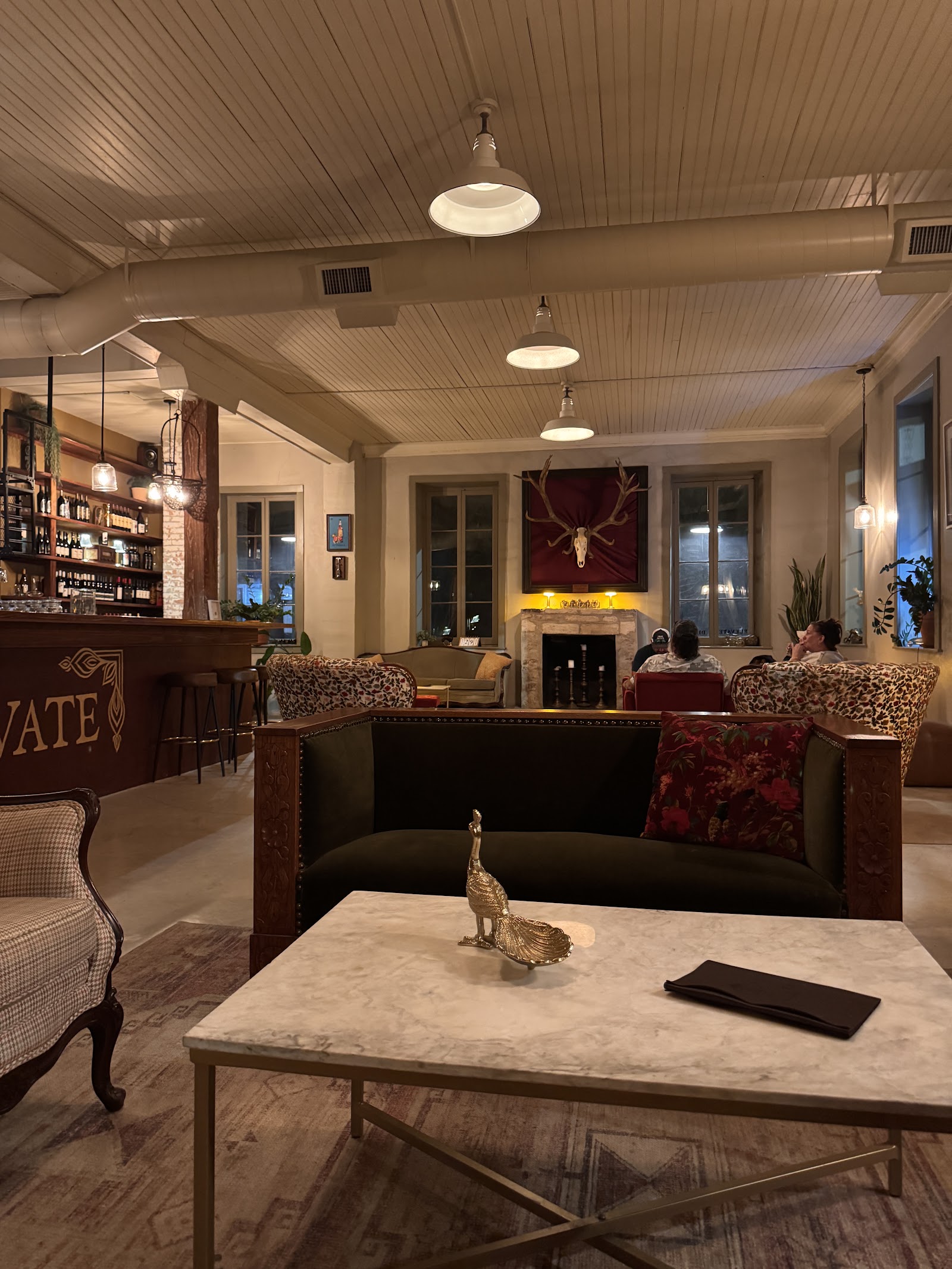The lounge at Blu Lacy Bar with leather sofas, a stone fireplace, and mounted antlers